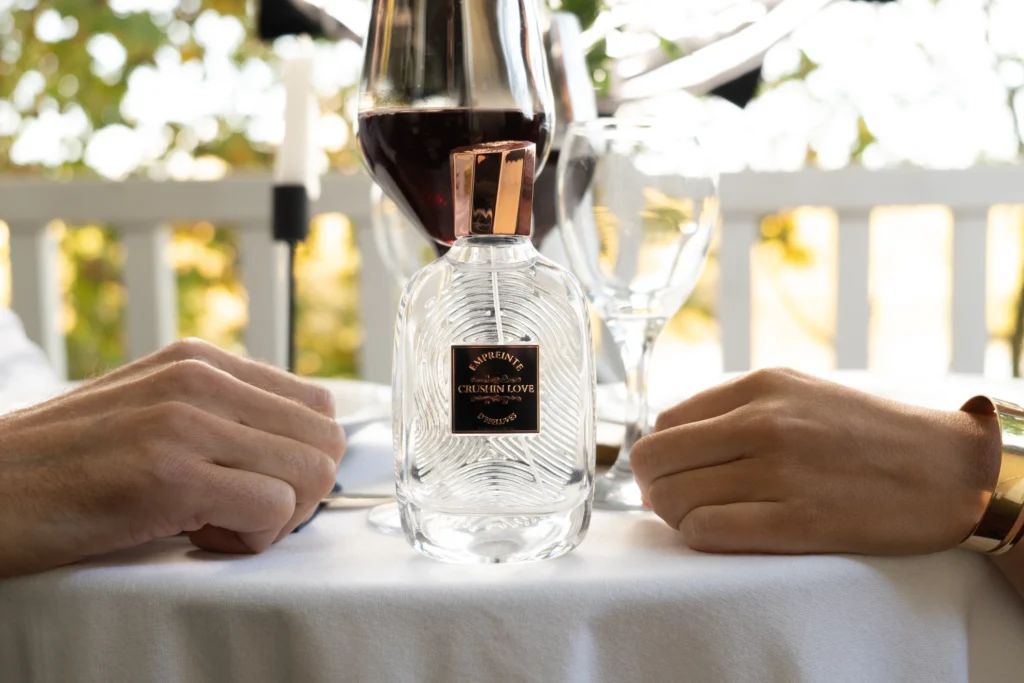 Flacon Crushin love sur une table dressée, deux mains posées de part et d'autre